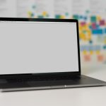 A sleek laptop on a table with a blurred background of colorful sticky notes