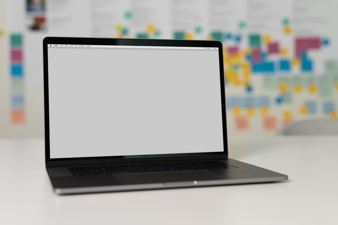 A sleek laptop on a table with a blurred background of colorful sticky notes